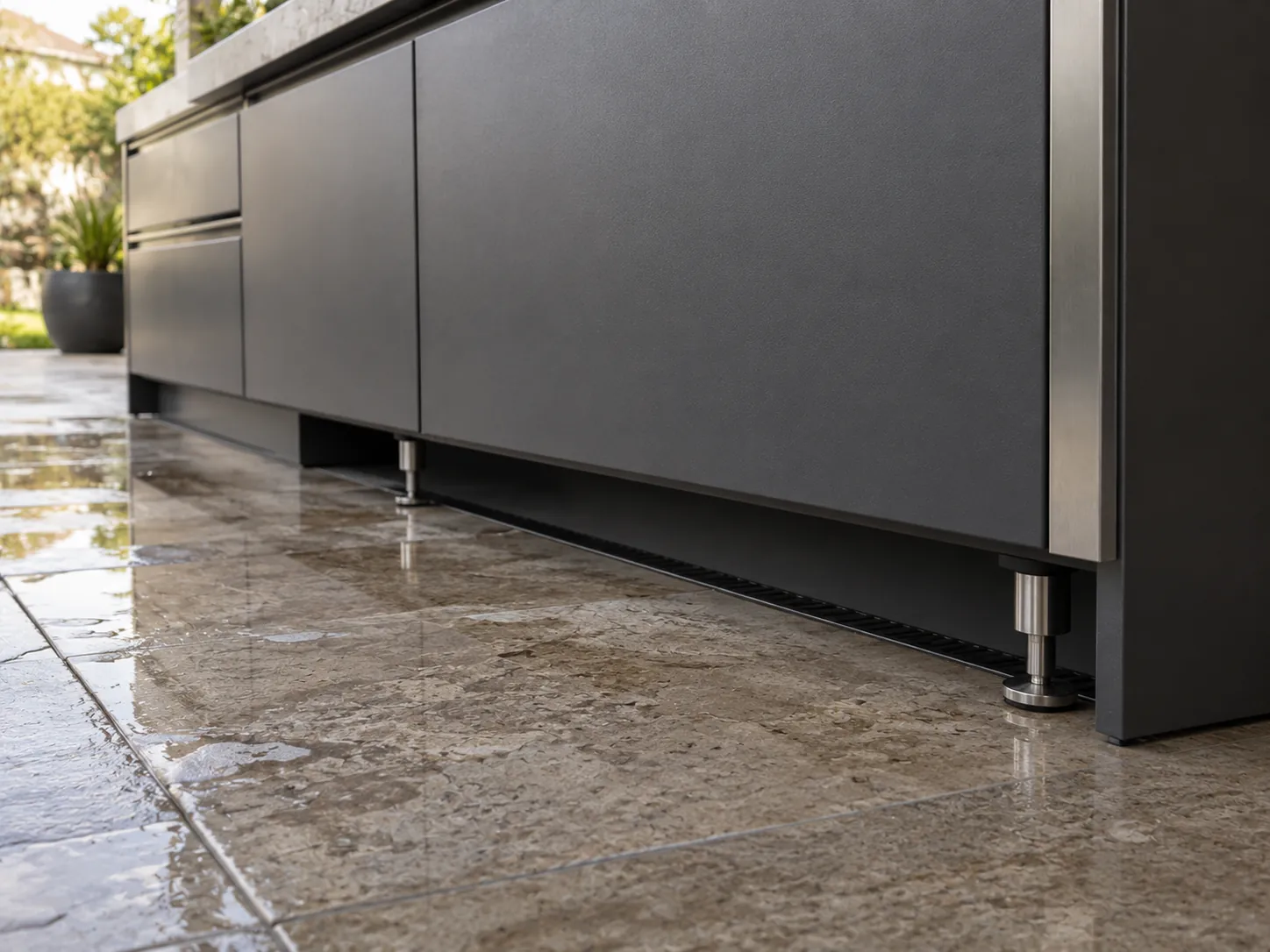 Raised outdoor cabinet base with drainage gap, stone patio floor, and clean toe kick detail.