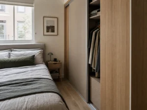 Compact bedroom with a wall-fitted sliding wardrobe beside the bed.