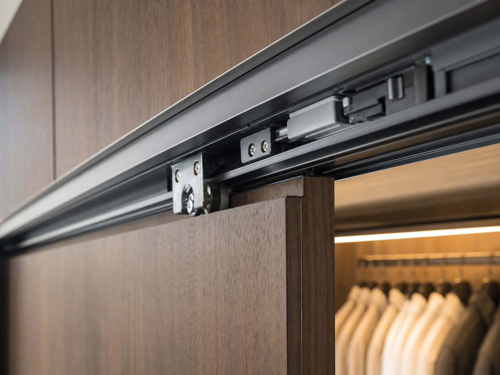 Close view of a sliding wardrobe track, rollers, and soft-close hardware.