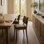 Narrow dining room with a pulled-out chair, low stone-top sideboard, and a clear walking route.
