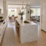 Single waterfall stone island with separate working and household routes in an open-plan kitchen.